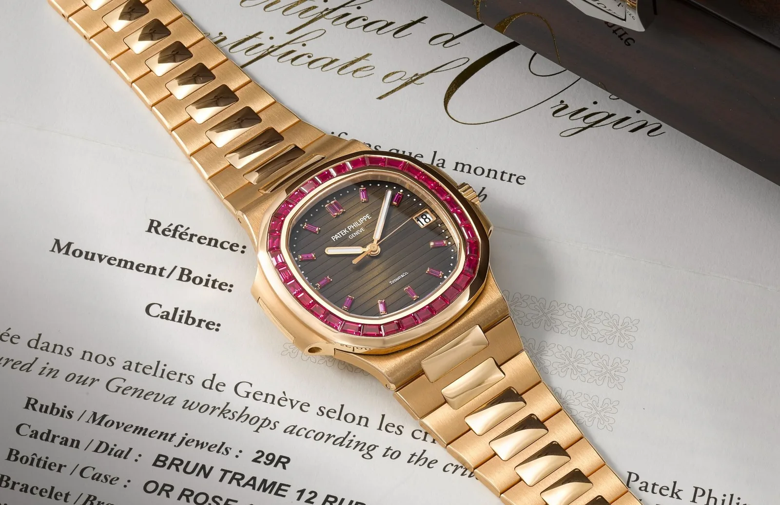 Patek Philippe Nautilus 5723/112R-001 in rose gold on a rose-gold bracelet, with a ruby-set bezel and sunburst brown dial, lying on a Patek Philippe Certificate of Origin