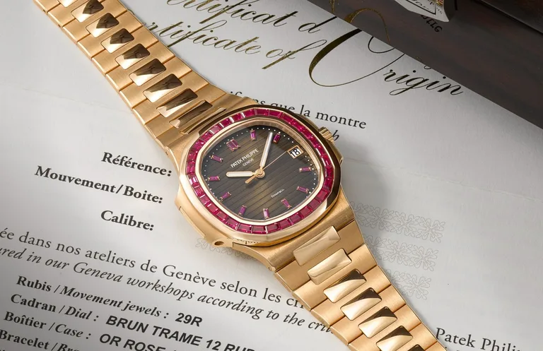Patek Philippe Nautilus 5723/112R-001 in rose gold on a rose-gold bracelet, with a ruby-set bezel and sunburst brown dial, lying on a Patek Philippe Certificate of Origin